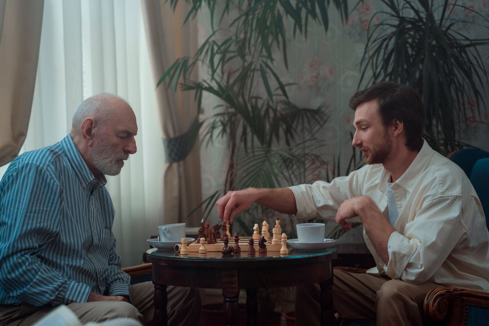 A father and his adult son playing chess at home