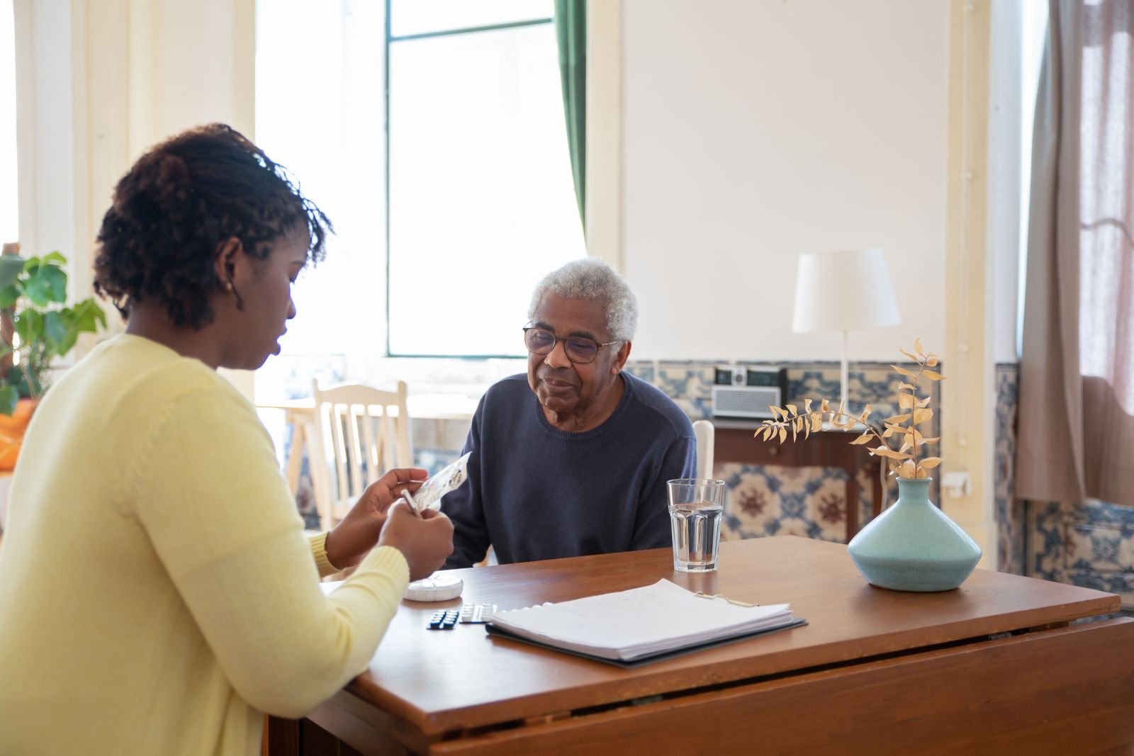 A caregiver helping an older man at his kitchen table
